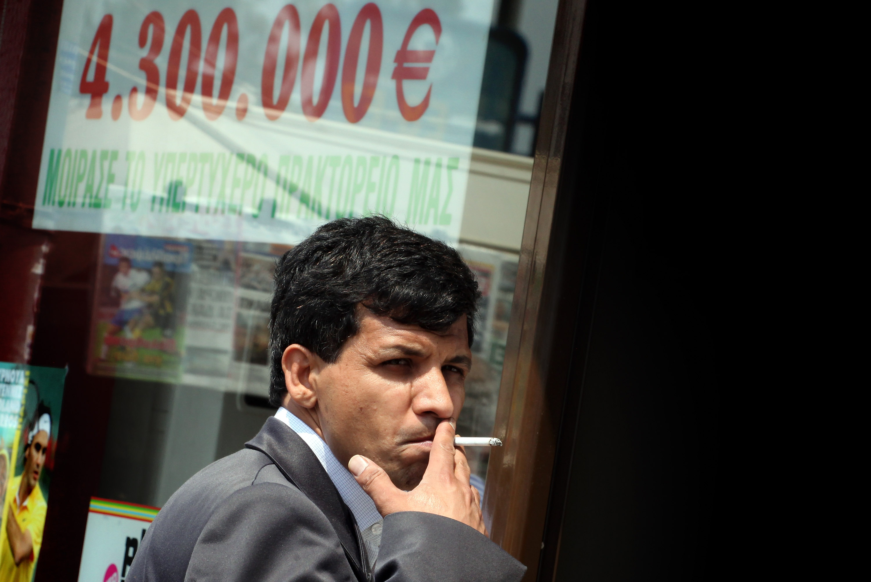 ATHENS, GREECE - MAY 31:  A man smokes a cigarette before entering a betting shop on May 31, 2011 in Pireas, the port of Athens, Greece. The Greek government is trying to implement a further round of severe austerity measures after EU finance officials have argued that the country, which is already struggling to meet the terms of an international euro110 billion bailout, could require even more help.  (Photo by Matt Cardy/Getty Images)